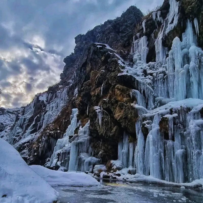 Massive icicles hanging from the rocky cliffs at Drung Waterfall.jpg