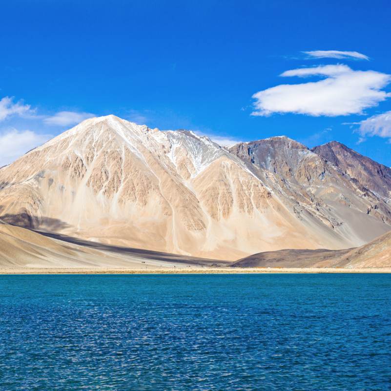 Still morning reflection on Pangong Lake before the wind picks up, the short early window most photographers plan their overnight stay around