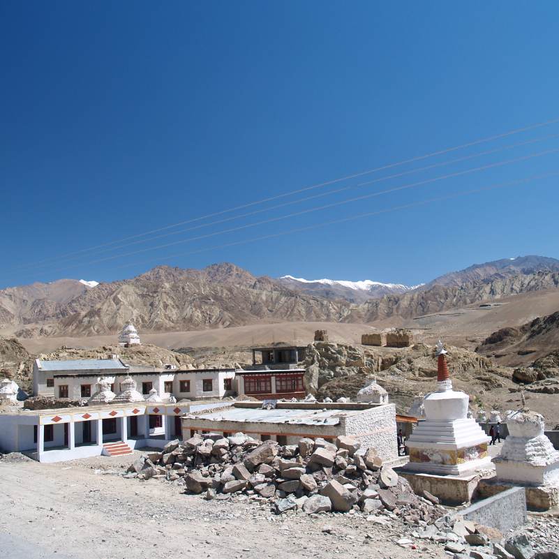 Whitewashed Alchi Monastery buildings with barren Ladakh mountains rising behind