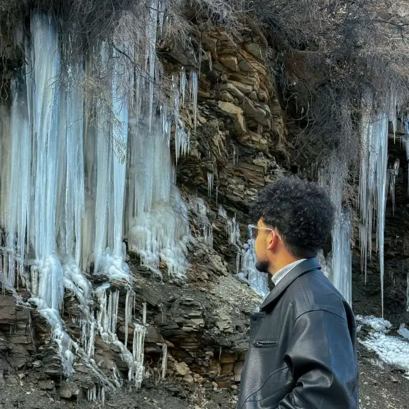 The Sissu Waterfall frozen into an ice column in winter, visible from the lake area