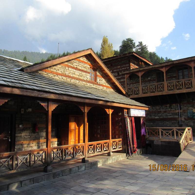 Stone and wood walls of Naggar Castle with Himalayan hills in the background